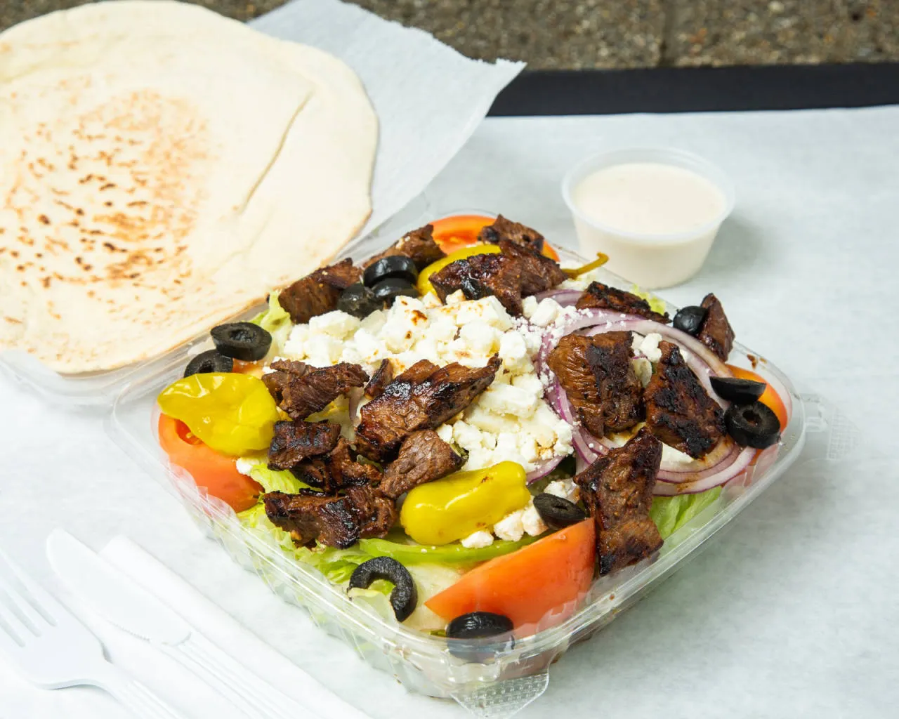 Greek salad topped with steak tips and feta